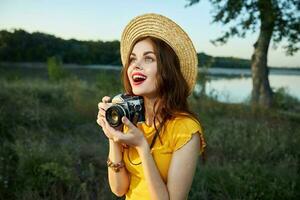 femme avec une caméra regards en haut dans une chapeau rouge lèvres ouvert bouche la nature photo