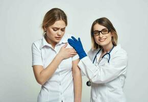 femelle médecin dans une médical robe et bleu gants examine une patient dans une tondu vue photo
