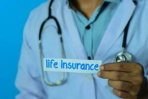 médecin en portant une carte avec texte la vie assurance. médical et soins de santé concept. photo