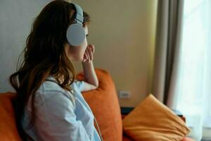 jolie femme séance sur le canapé à Accueil écoute à la musique sur écouteurs appartements photo