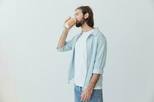 free-lance millénaire homme avec barbe en buvant café de une Crabe tasse dans élégant branché vêtements sur une blanc Contexte photo