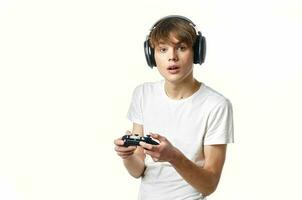 gars dans une blanc T-shirt dans écouteurs avec une manette vidéo Jeux La technologie joueur photo