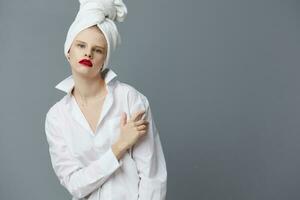 femme avec une serviette sur le sien tête dans une blanc chemise studio modèle inchangé photo