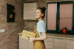 jolie femme dans une marron tablier Coupe planche cuisine intérieur inchangé photo