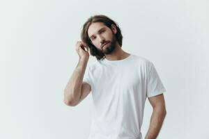 portrait de une homme avec une noir épais barbe et longue cheveux dans une blanc T-shirt sur une blanc isolé Contexte émotion de tristesse et désir photo