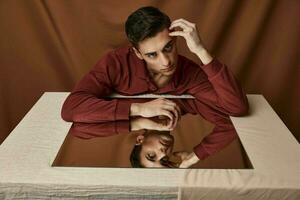 une homme est assis à une table avec une miroir à l'intérieur et une en tissu Contexte photo