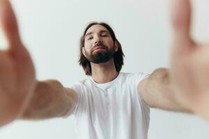 content adulte homme avec une barbe sourit et tire le cuisinier dans le caméra écoute à la musique dans écouteurs dans une affligé T-shirt sur une blanc isolé Contexte photo