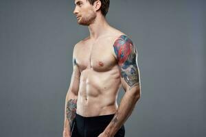 sportif homme avec pompé en haut presse tatouage sur le sien bras macho tondu vue photo