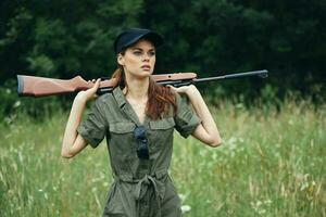 militaire femme en portant une arme derrière le sien retour noir casquette chasse mode de vie vert salopette photo