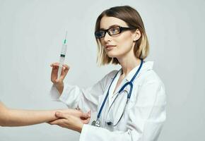 une femme médecin dans une médical robe est donnant un injection à une patient photo