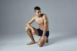 sportif homme avec musclé corps dans noir short isolé Contexte squat photo