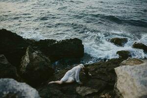 femme mensonge sur rocheux côte avec des fissures sur rocheux surface paysage photo