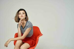 femme dans une rayé T-shirt séance sur le rouge chaise tondu vue charme photo