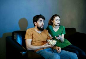 Beau homme et Jeune femme sur canapé à l'intérieur en train de regarder la télé dans le soir photo