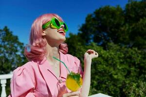 Jeune femelle dans vert des lunettes de soleil avec cocktail dans été en plein air relaxation concept photo