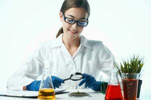 femme biologiste blanc manteau séance à le table recherche plante photo