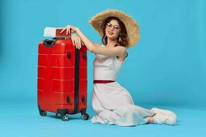 de bonne humeur femme avec rouge valise séance sur le sol émotions isolé Contexte photo