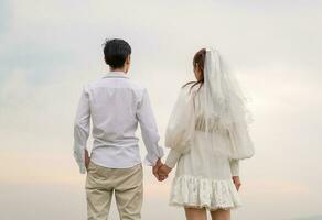 heureux jeune couple asiatique en vêtements de mariée et de marié photo