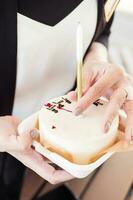 bento gâteau avec une bougie avec une les filles main, gros plan. peu surprise pour une les filles anniversaire photo