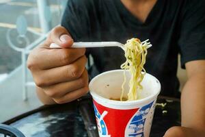 instant nouilles, nouille soupe dans une tasse, garçons main alimentation prêt à manger nouilles photo