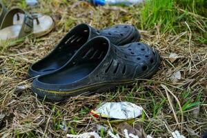 une paire de terne noir Plastique des sandales sur sec herbe photo