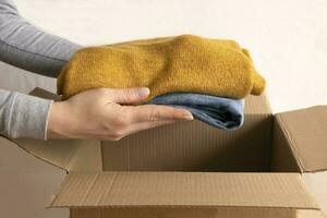 femme packs vêtements dans des boites pour faire un don. photo