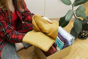 femme packs vêtements dans des boites pour faire un don. photo