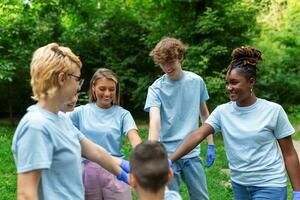 groupe de multiracial volontaire Jeune gens bâtiment équipe Extérieur dans parc, joindre mains ensemble. photo