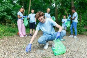 faire du bénévolat, charité, nettoyage, gens et écologie concept - groupe de content bénévoles avec des ordures Sacs nettoyage zone dans parc photo