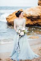 mariée avec un bouquet de fleurs sur la plage