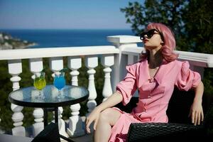 attrayant femme dans des lunettes de soleil en plein air sur le terrasse cocktail relaxant inchangé photo