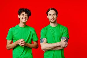 deux Hommes dans vert t-shirts sont permanent suivant à relation amicale rouge Contexte photo