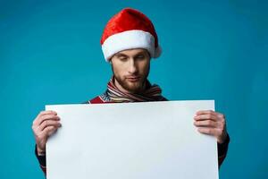 de bonne humeur homme dans une Père Noël chapeau en portant une bannière vacances bleu Contexte photo