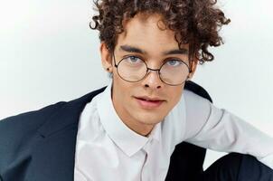 fermer portrait de Beau gars avec frisé cheveux portant des lunettes et dans une classique costume photo