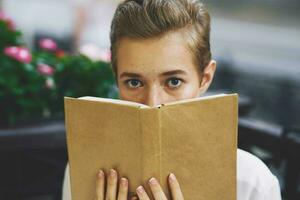 étudiant avec une livre dans le sien mains en train de lire marcher dans le Frais air éducation photo