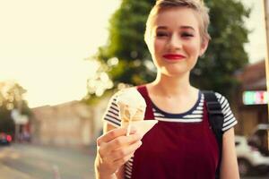 femme avec court cheveux sur le rue avec la glace crème dans sa mains amusement photo