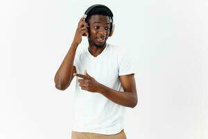 une homme de africain apparence avec écouteurs écoute à la musique dans une blanc T-shirt photo