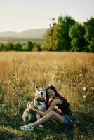 femme séance dans champ avec teckel chien souriant tandis que dépenses temps dans la nature avec ami chien dans l'automne à le coucher du soleil tandis que en voyageant photo