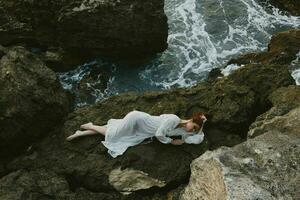 magnifique femme dans une blanc robe mensonge sur une pierre dans une blanc robe vacances concept photo