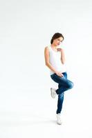 fille gaie dans un t-shirt blanc et un jean bleu foncé en studio sur fond blanc photo