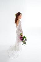 mariée fille joyeuse dans une robe tricotée blanche posant avec un bouquet de fleurs photo