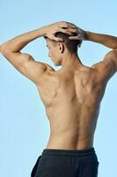 athlète bodybuilder détient le sien bras derrière le sien retour pompé en haut bras muscles retour vue photo