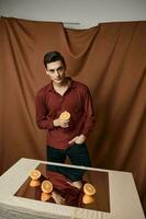 tranché des oranges sur le table et réfléchissant miroir homme en tissu Contexte photo