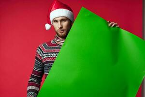 émotif homme dans une Père Noël chapeau en portant une bannière vacances rouge Contexte photo