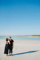 jeune couple un mec avec une fille en vêtements noirs marchent sur le sable blanc photo