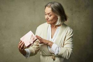 personnes âgées femme dans une pansement robe avec une cadeau dans sa mains anniversaire se soucier photo