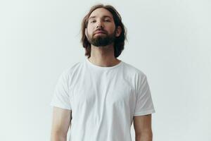 portrait de une de bonne humeur homme avec une noir épais barbe et longue cheveux avec une gentil sourire dans une blanc T-shirt sur une blanc isolé Contexte photo