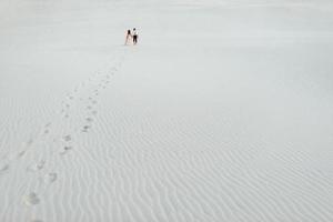 jeune couple un mec en culotte noire et une fille en robe rose marchent le long du sable blanc photo