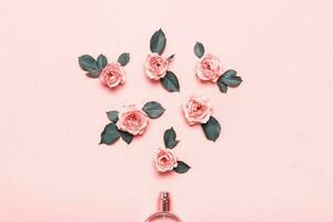 bouteille de parfum et des roses fleurs sur rose Contexte. minimal beauté concept photo