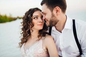 jeune couple un mec en culotte noire et une fille en robe rose marchent le long du sable blanc photo